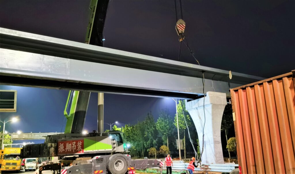 Beam launching in progress using mobile cranes.