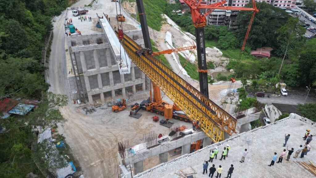 A precast beam is being lifted onto the launching truss for span erection.