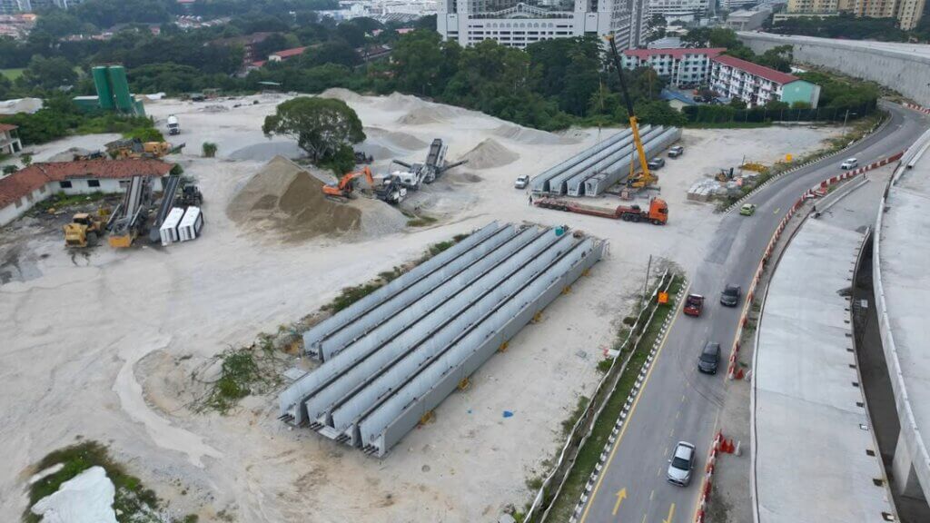 The precast UHPC bridge girders have been delivered, unloaded, and temporarily stored at the site laydown area, pending lifting and launching onto the designated piers and abutments