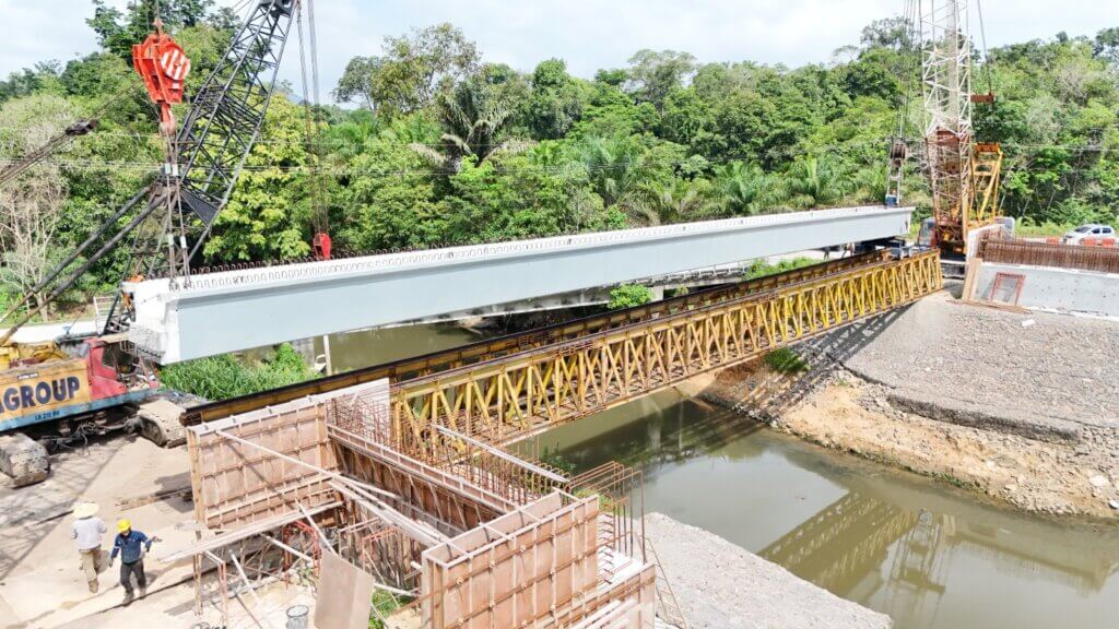 Beams are transferred to the launching truss and rolled to the opposite abutment for positioning.