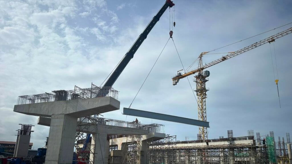 Beam lifting in progress for transfer to the piers using a crane.