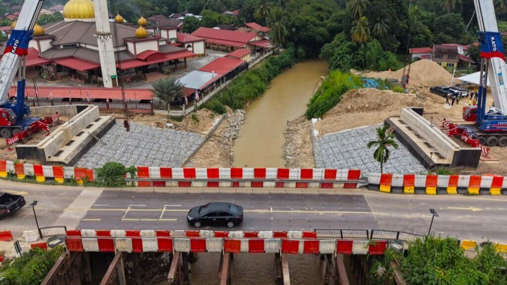 Preparatory works are underway at the site for the launching of the bridge beams, with lifting cranes positioned on both banks of the river.